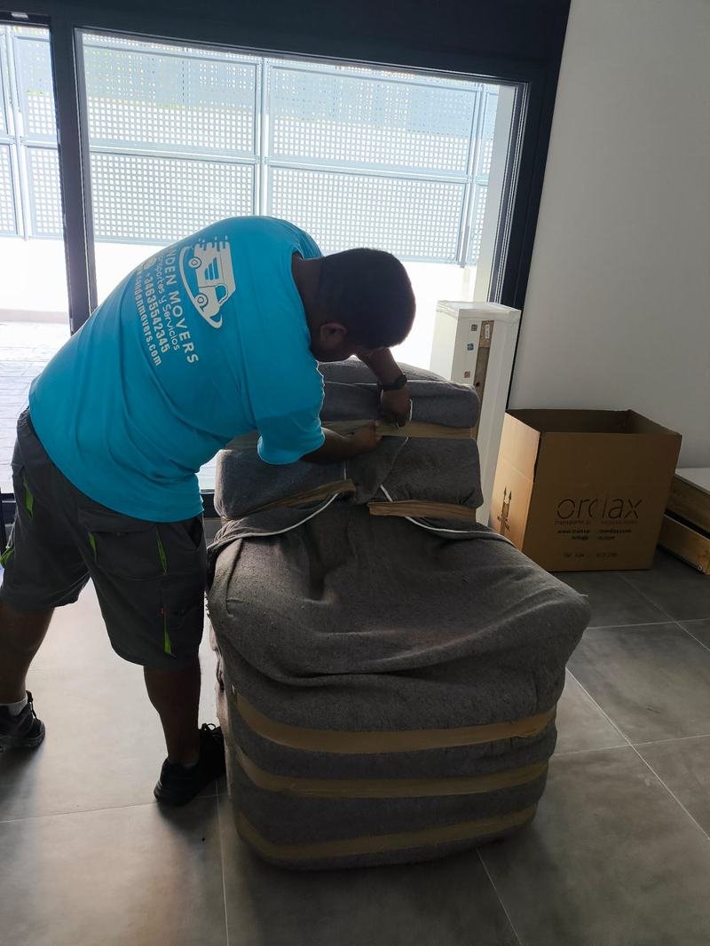 Un miembro del equipo envuelve un sillón con una manta antes de moverlo