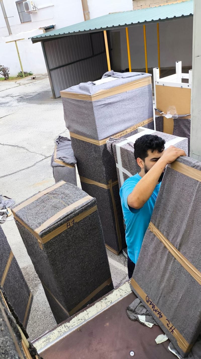 Un miembro del equipo carga un mueble envuelto en manta